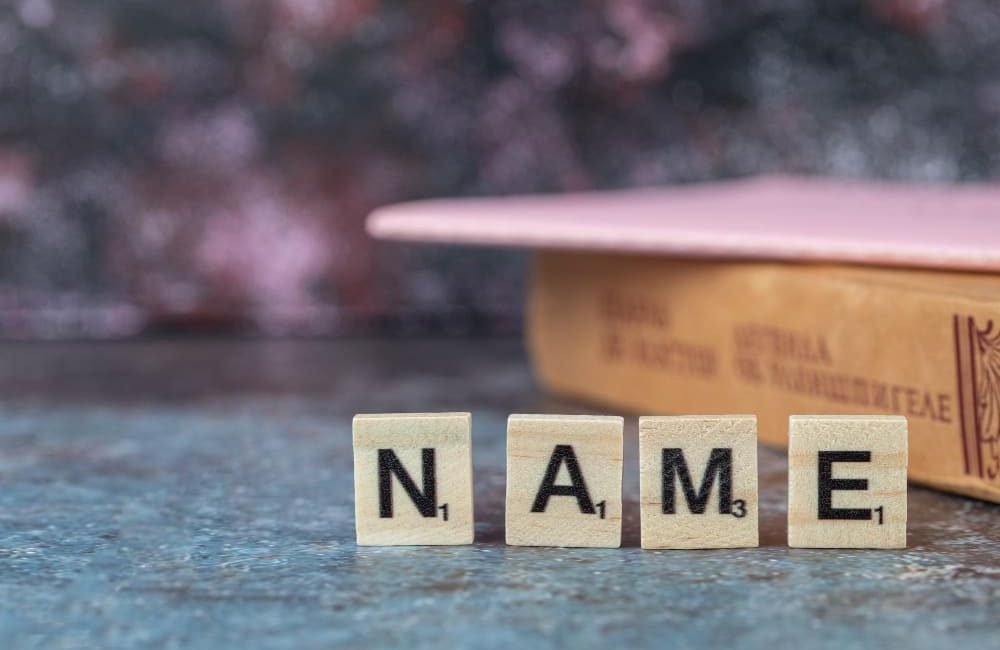 name-writing-with-black-letters-wooden-dices-with-old-book-around-high-quality-photo